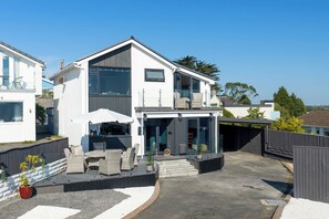 Ein modernes, zweistöckiges Haus mit Balkon, Außenbereich und Garage.