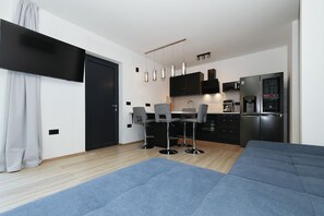 Ett modernt kök med kylskåp, mikrovågsugn och kaffebryggare. Det finns en matplats med ett bord och stolar.