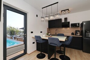 A modern kitchen with a dining area, a pool view, and a black refrigerator. - Beachfront Almare Retreat (Sukošan)