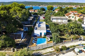 A residential area with a swimming pool, surrounded by trees and houses. - Beachfront Almare Retreat (Sukošan)