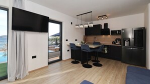 A modern kitchen with a large island, bar stools, a built-in microwave, and a refrigerator. - Beachfront Almare Retreat (Sukošan)