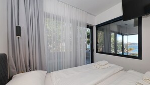 A hotel room with a bed, a large window with a view, and sheer curtains. - Beachfront Almare Retreat (Sukošan)