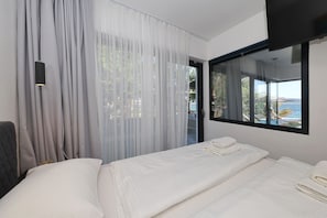 A hotel room with a bed, a large window with a view, and sheer curtains. - Beachfront Almare Retreat (Sukošan)