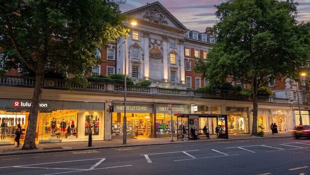 Une vue de rue d’un immeuble comportant plusieurs boutiques, dont une librairie « Waterstones » bien visible.