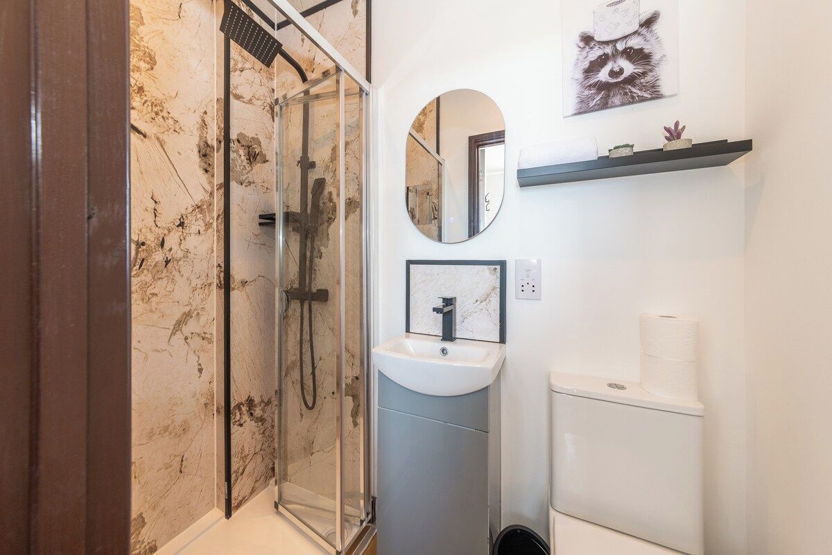 Une salle de bain avec une douche à parois de verre, un lavabo blanc et des toilettes.