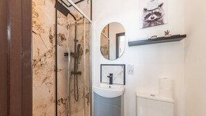 A modern bathroom with a glass shower enclosure, a sink with a marble countertop, and a toilet. - New Kensington High Street Studio with AC (Greater London)