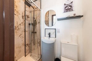 A modern bathroom with a glass shower enclosure, a sink with a marble countertop, and a toilet. - New Kensington High Street Studio with AC (Greater London)