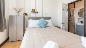 A bedroom with a bed, a wardrobe, a bedside table, a mirror, and a shower area. - New Kensington High Street Studio with AC (Greater London)