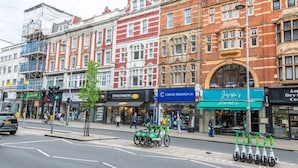 A street with buildings, a cyclist, and a row of scooters. - New Kensington High Street Studio with AC (Greater London)