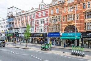 A street with buildings, a cyclist, and a row of scooters. - New Kensington High Street Studio with AC (Greater London)