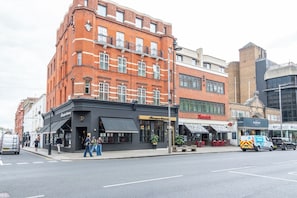 A street view with a row of buildings, including a restaurant named 'Washington Hotel' and a 'Vanders' store. - Prism Kensington - New Studio - Airconditioned (Greater London)