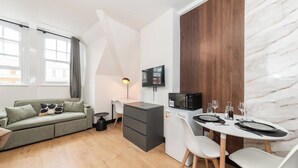Ett kompakt bostadsutrymme med ett litet kök, en matplats och en soffa.