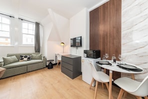 Un espace de vie compact comprenant un coin cuisine, un coin repas et un canapé.