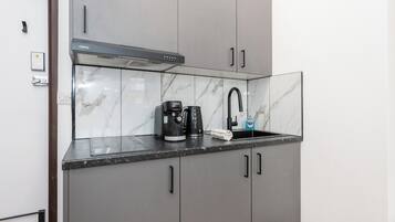 A compact kitchen with a built-in coffee maker, a sink, and a modern stove hood.