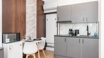 A compact kitchen with a microwave, coffee maker, and a small dining area with two chairs.