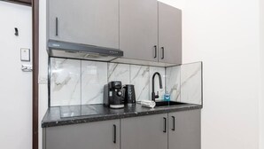 A kitchen with a coffee maker, a sink, and a cabinet. - Stylish New Studio in Kensington with AC (Greater London)