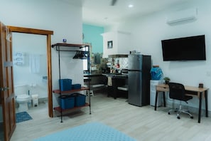 A compact living space with a kitchenette, a TV mounted on the wall, and a desk with a chair. - Centrally located walking distance from restaurants, Mercadito, etc... (Isla Mujeres)