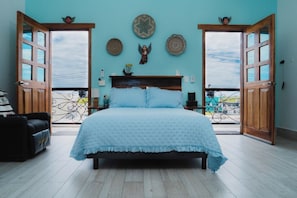 A bedroom with a bed, a balcony door, and decorative wall hangings. - Centrally located walking distance from restaurants, Mercadito, etc... (Isla Mujeres)