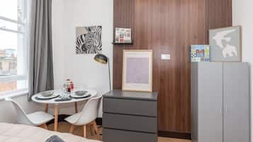 A modern bedroom with a bed, a desk with a chair, a wardrobe, and artwork on the walls.