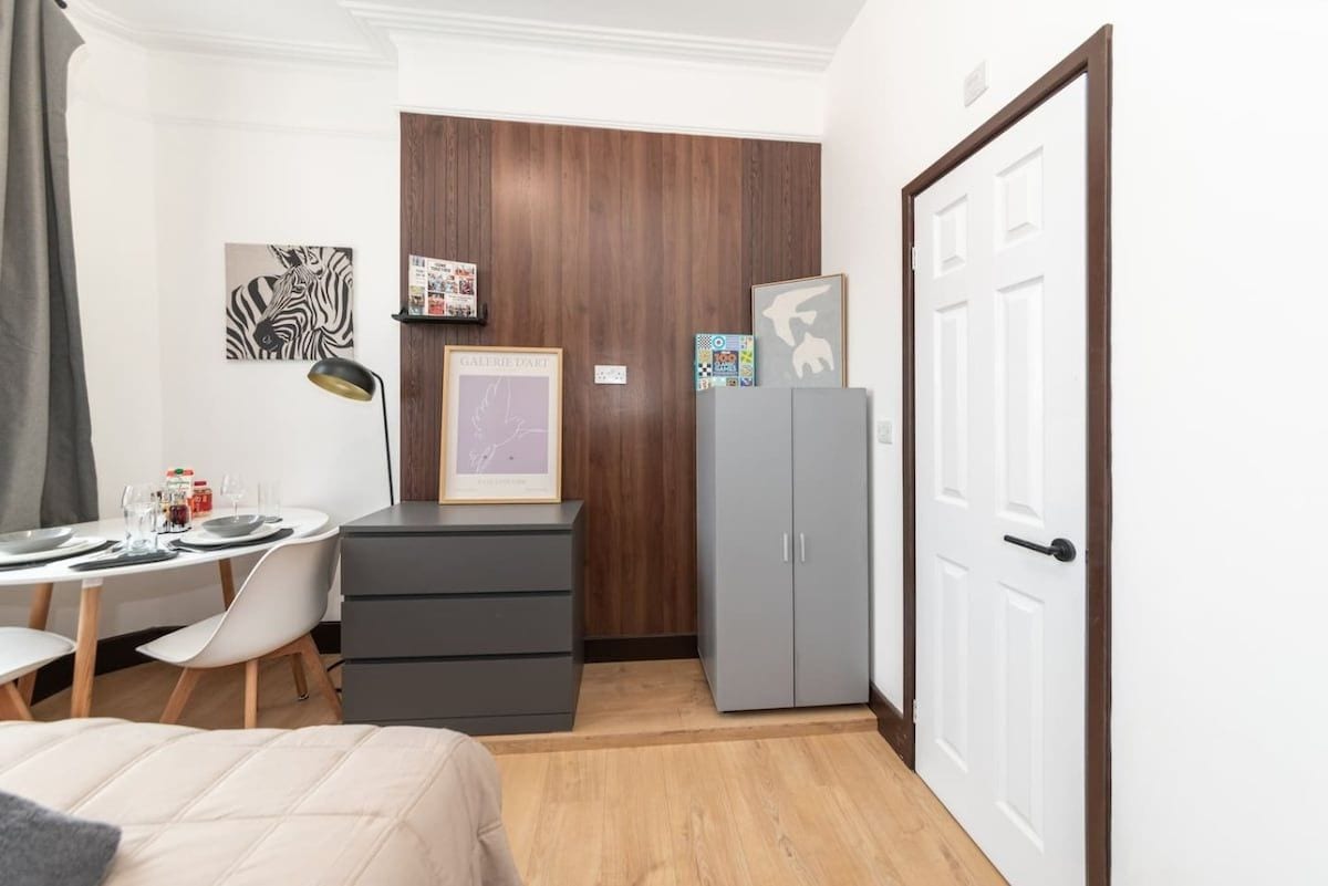 Een kleine kamer met een bed, een bureau met stoel, een kledingkast en een deur.