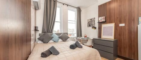 A bedroom with a bed, bedside table, and a dresser.