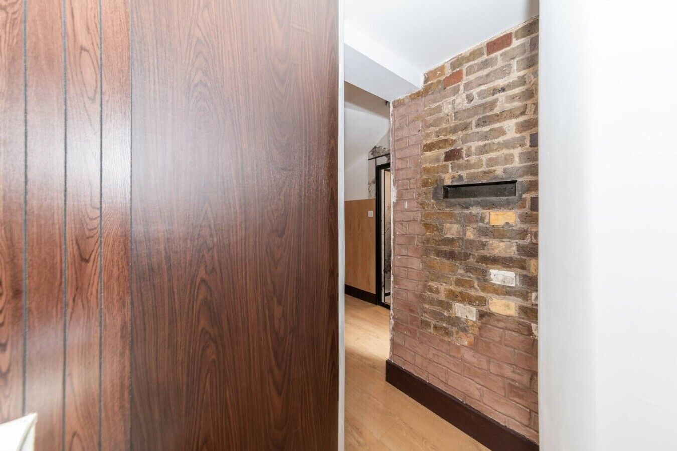 A wooden door and a brick wall with a mailbox.