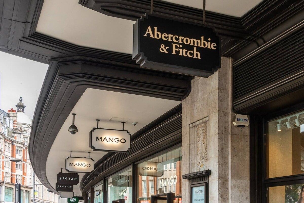 A street view with a building facade featuring a sign for 'Abercrombie & Fitch' and multiple 'Mango' store signs.