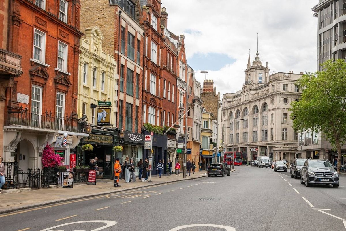A street with buildings, a café, and parked cars.