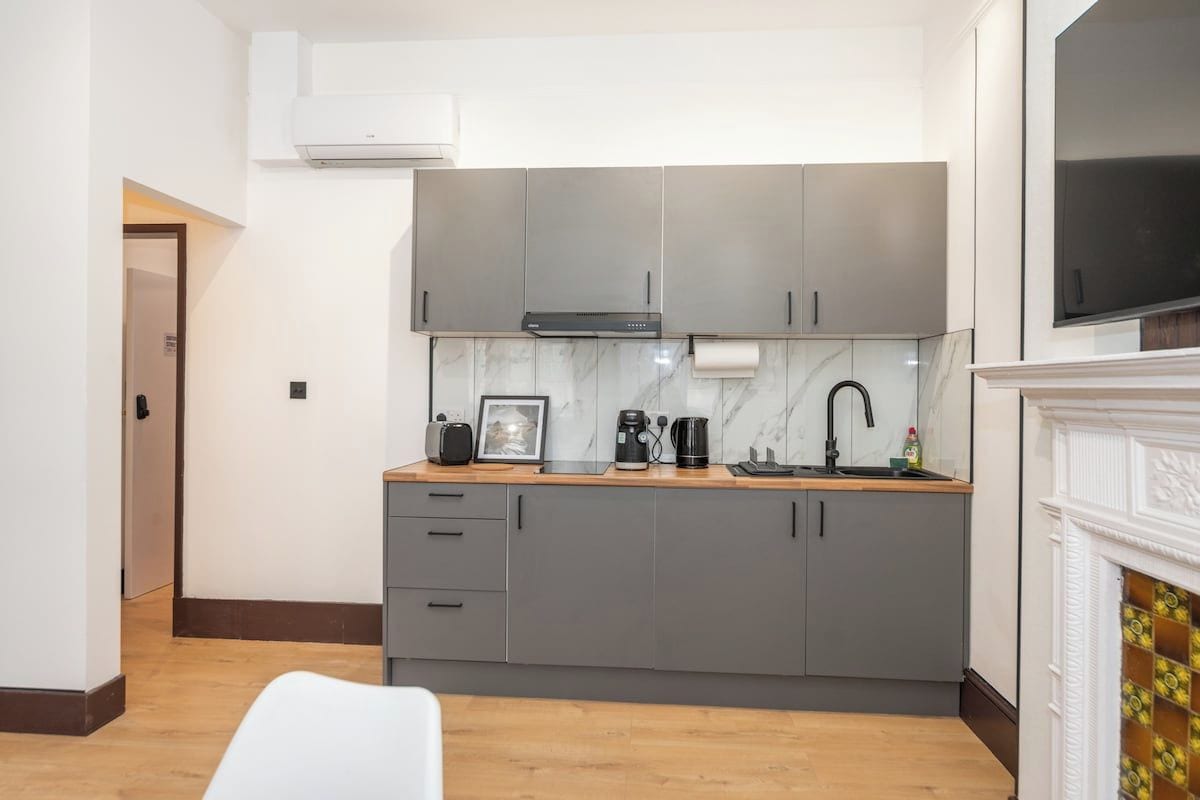 A modern kitchen with grey cabinets, a marble backsplash, and a built-in oven.