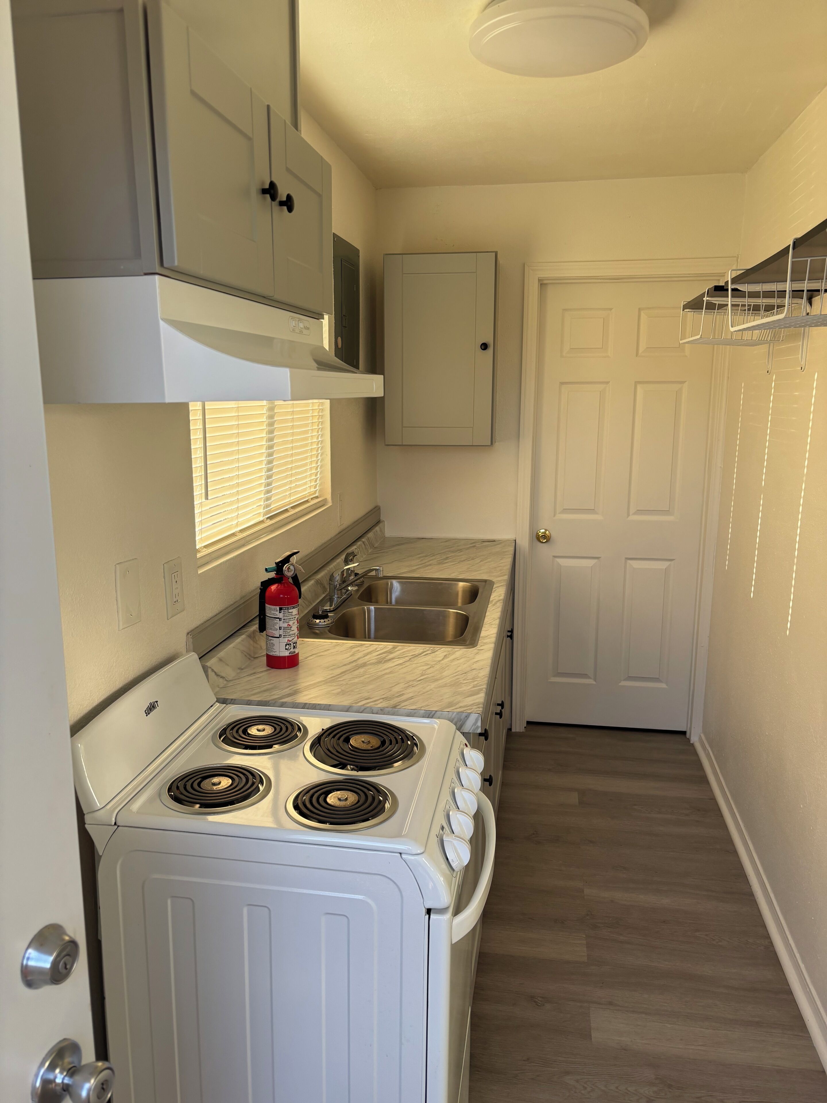 A compact kitchen with a stove, sink, and cabinets.