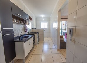 A modern kitchen with a gas stove, a dishwasher, and a built-in oven. - Apt with Balcony & Parking 300m | Vila Tupi Beach (Praia Grande)