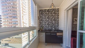 Ett litet kök med kakel på väggen bakom diskbänken, en diskho och ett fönster med utsikt över stadsbilden.