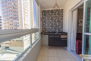 Eine kleine Küche mit gefliestem Spritzschutz, einem Spülbecken und einem Fenster mit Blick auf eine Stadtlandschaft.