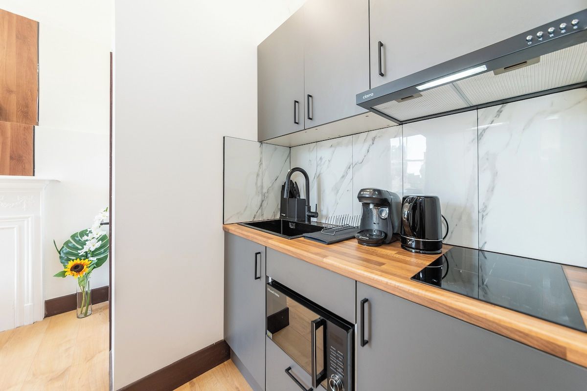 A modern kitchen with a marble backsplash, stainless steel appliances, and a wooden countertop.