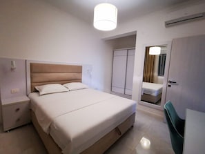 A hotel room with a bed, bedside tables, a desk, a chair, a wardrobe, and a mirror. - Villa Blue Panorama 2 - Private Pool & Sea View in Budva (Budva)