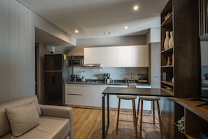 A modern kitchen with white cabinets, a wooden dining table, and bar stools. - Centric & luxury suite w sauna, jacuzzi & gym (Mexico City)