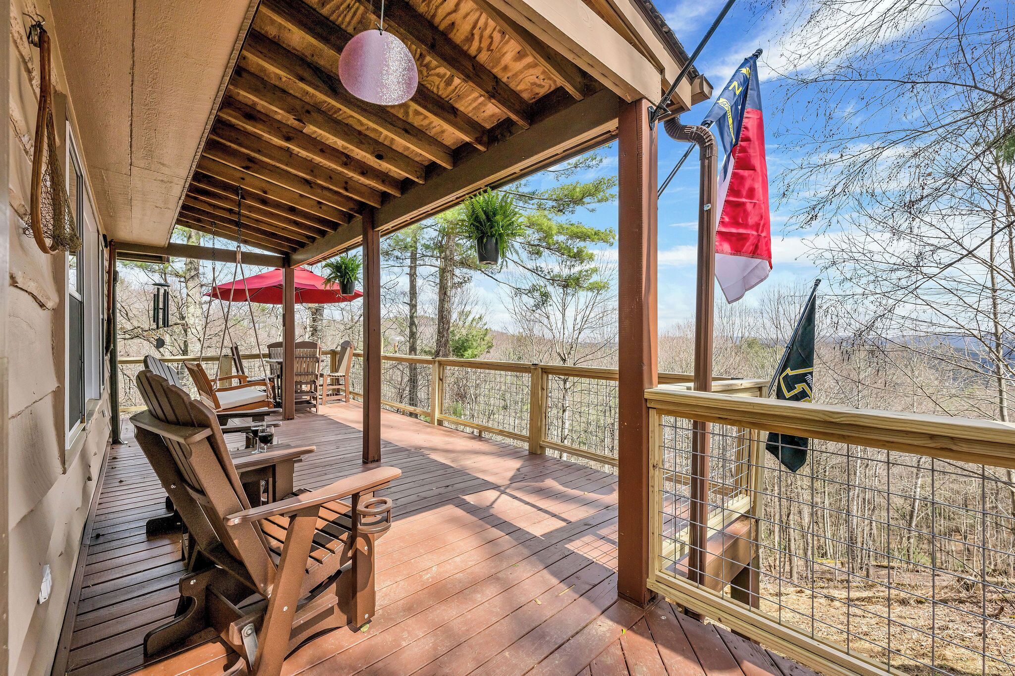 Terraza de madera con asientos exteriores y vistas a un bosque.