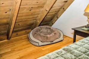 Un panier pour animal de compagnie dans une pièce dont le plafond est orné de poutres en bois et le sol est recouvert de planches de bois.