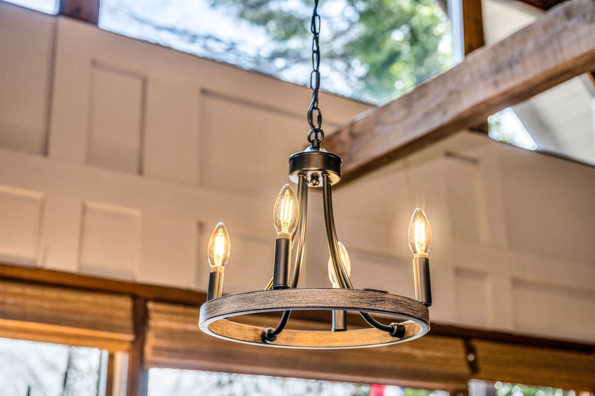 A chandelier with multiple bulbs, hanging from a ceiling with a wooden beam structure.