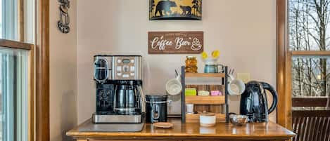Una estación de café con una cafetera Cuisinart, una olla de cocción lenta Veken y un letrero de barra de café.