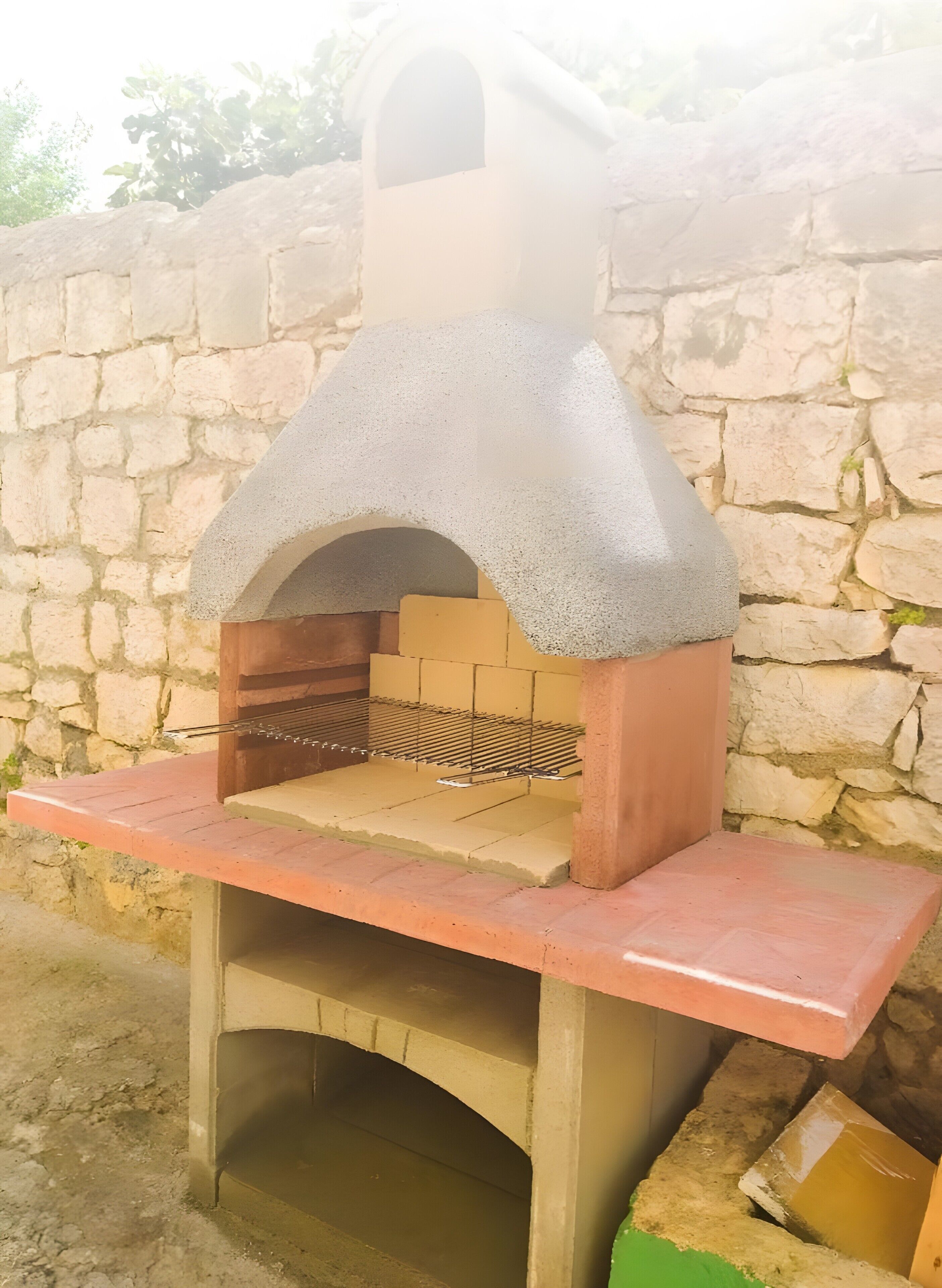 A stone-built outdoor oven with a metal grill shelf.