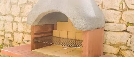 Un horno de piedra al aire libre con repisa metálica para parrilla.