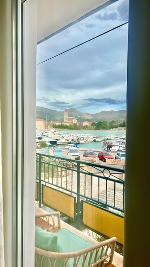 A balcony with a view of a marina, boats, and a distant building with a tower. - Apartment 'Čagalj Trogir' with Sea View, Wi-Fi and Air Conditioning (Trogir)