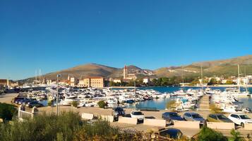 A marina with boats docked, a clear sky, and a hilly landscape in the background.