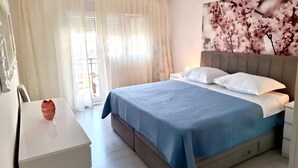 A bedroom with a bed, a bedside table, a chair, and a window with curtains. - Apartment 'Čagalj Trogir' with Sea View, Wi-Fi and Air Conditioning (Trogir)