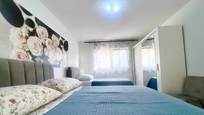 A bedroom with a large bed, two smaller beds, a wardrobe, a mirror, and a window with curtains. - Apartment 'Čagalj Trogir' with Sea View, Wi-Fi and Air Conditioning (Trogir)