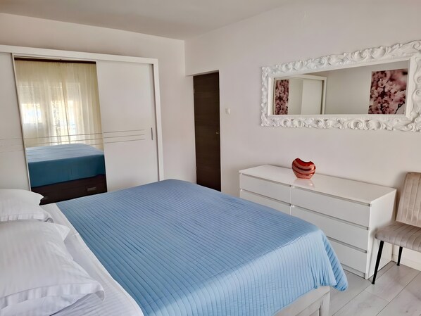Una camera da letto con un letto, una cassettiera, una sedia, uno specchio e un armadio.