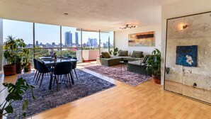 Amplia sala de estar con una mesa de comedor, sofás y vistas a la ciudad.