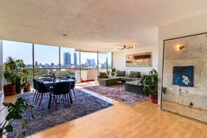 Ein geräumiger Wohnbereich mit Esstisch, Sofas und Blick auf die Stadt.
