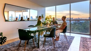 Un comedor moderno con un ventanal grande, vistas a la ciudad y una mesa con sillas.